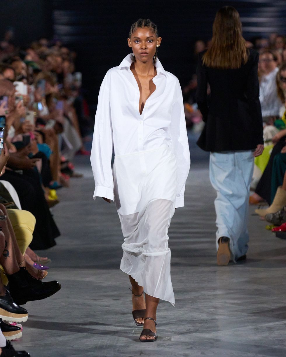 a model at tibi wears a white shirt dress with a sheer skirt on the bottom in a guide to how to wear sheer clothes in 2023