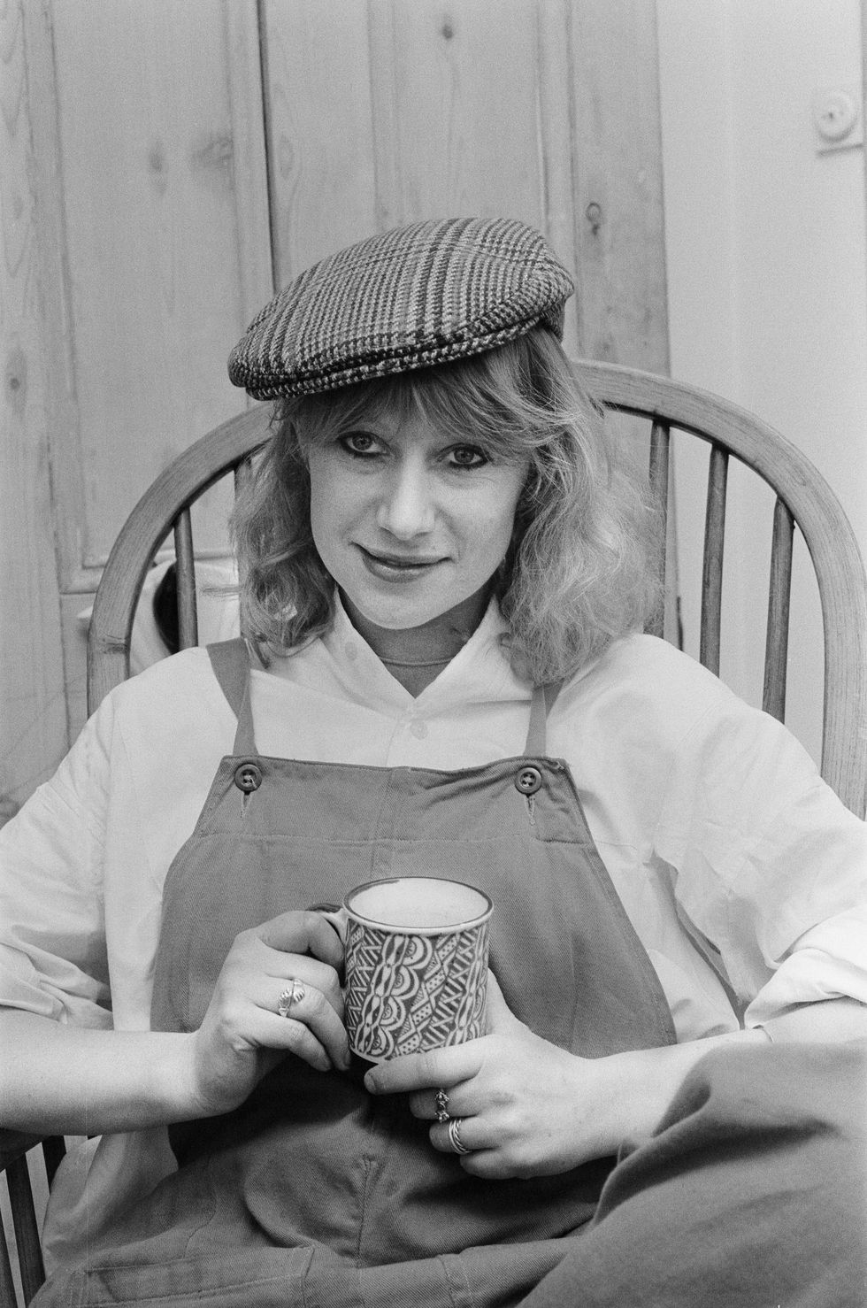 helen mirren seated in her country windsor chair wearing her favourite cap