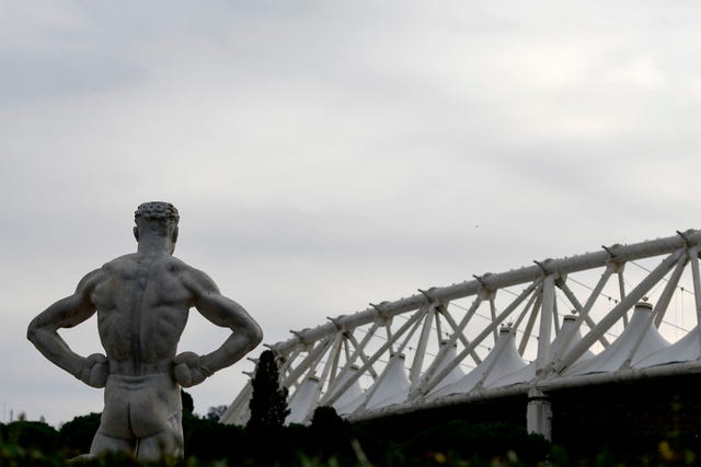 una de las estatuas del stadio dei marmi de roma con el estadio olímpico de fondo