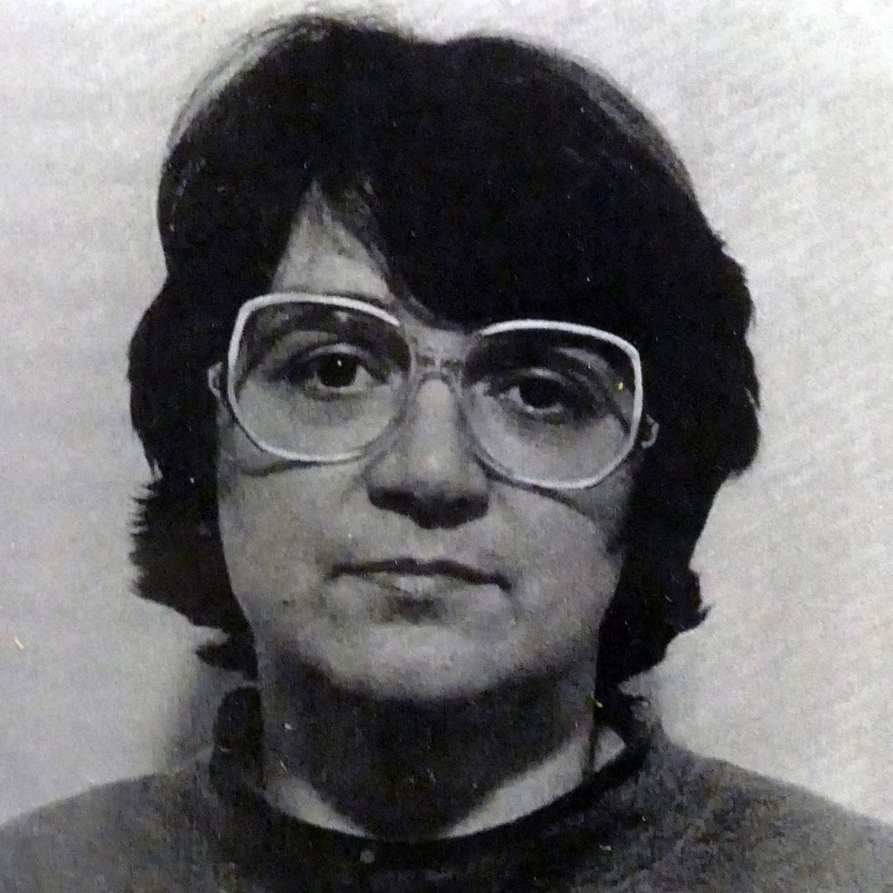 a mug shot of a woman with glasses and short hair staring at the camera