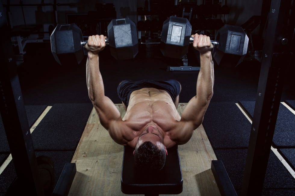 physical athlete doing dumbbell bench presses