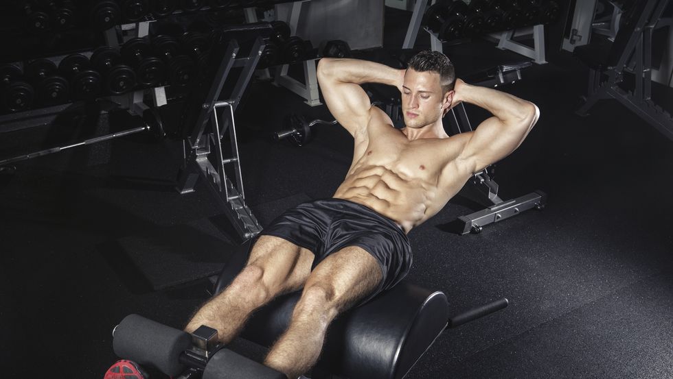 ragazzo che fa un macchinario per gambe in palestra senza maglia
