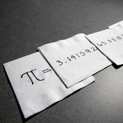 the number pi written across several white napkins on a grey surface