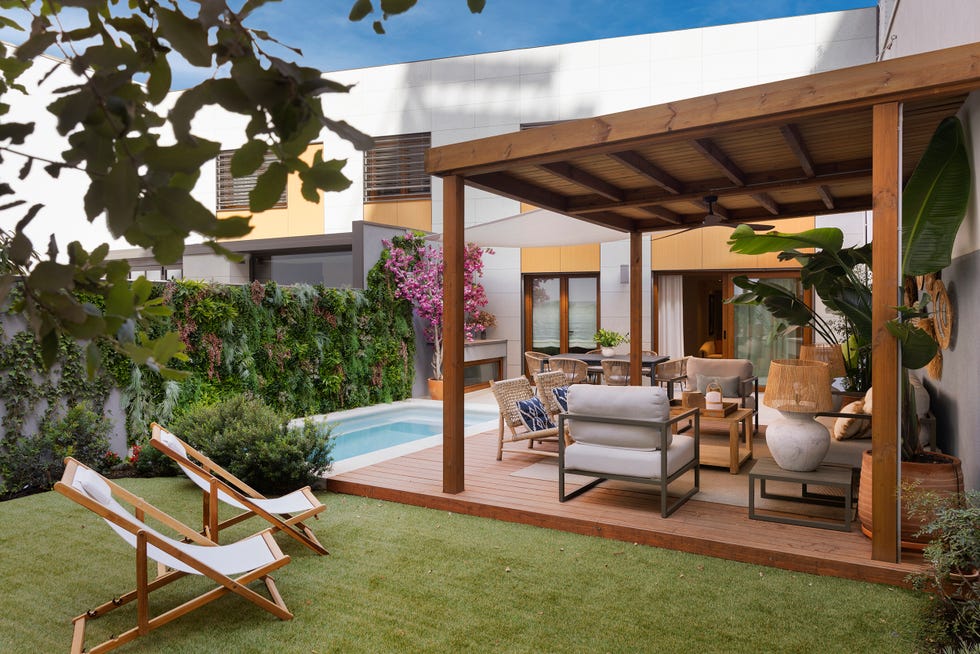 jardín con piscina y porche con muebles de fibras naturales
