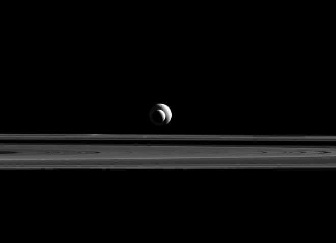 Tethys achter en Enceladus voor liggen op een lijn voor de camera van Cassini