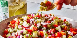 chopped pickles, tomatoes, and onions in a bowl with tortilla chips