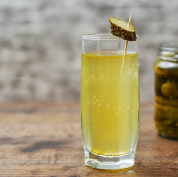 pickle juice in glass and a can of pickled cucumbers on wooden table background