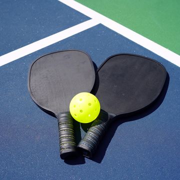 pickleball paddles and yellow ball on court