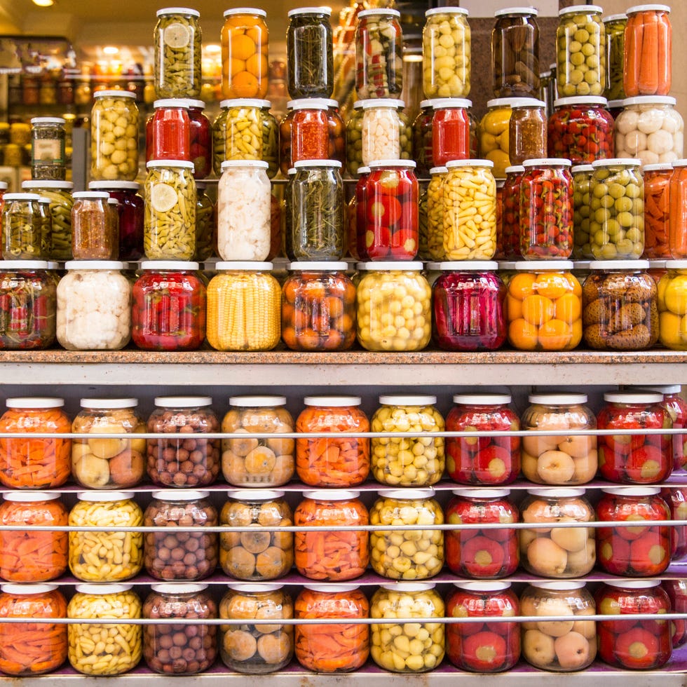 pickles in glass jars arranged on shelves at market for sale
