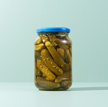 pickles, preserved gherkins in glass jar on green background