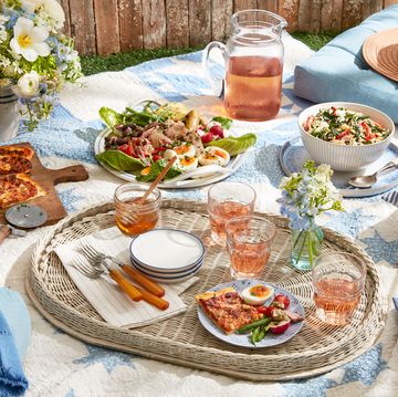 picnic foods, including flatbread, salad, and glasses of rose on a blanket