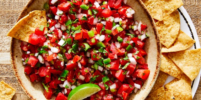 tomatoes, onion, peppers, and fresh cilantro mixed in a bowl with lime to make pico de gallo