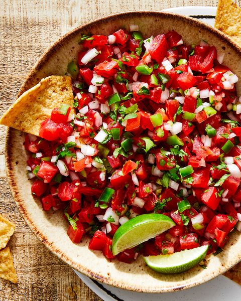 tomatoes, onion, peppers, and fresh cilantro mixed in a bowl with lime to make pico de gallo