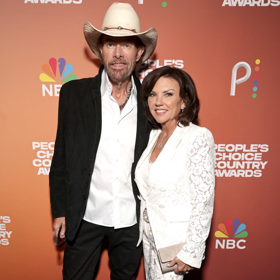 toby keith wearing a cowboy hat and posing for a photo with tricia lucus who wears all white