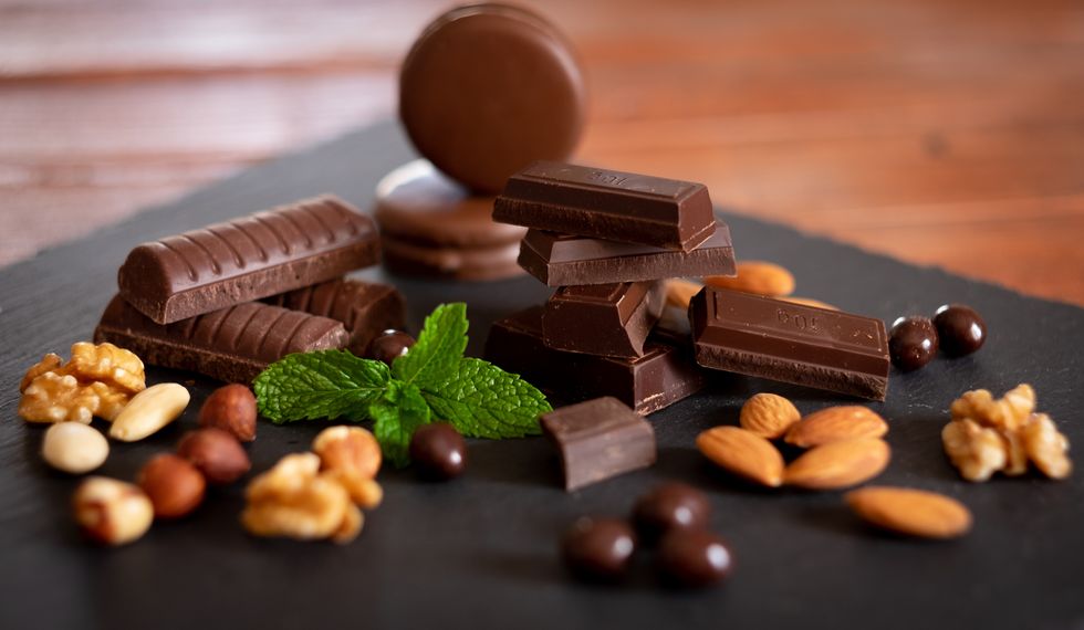 pieces of dark chocolate and dried fruit on black background wooden table and back lit