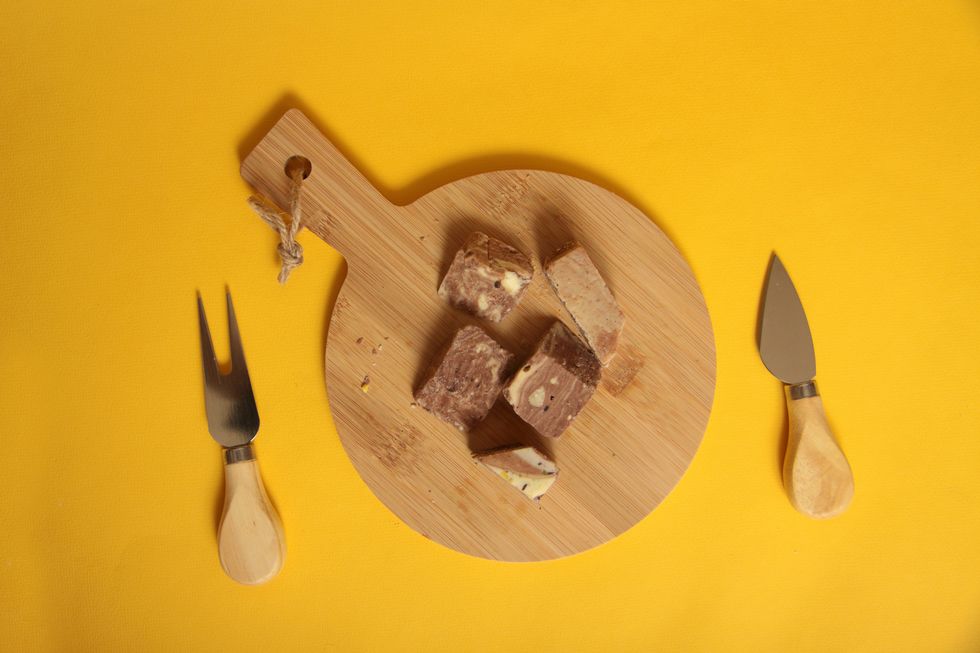 pieces of sherbet on wooden cutting board, knife and a fork on yellow background flat lay turkish delifght concept