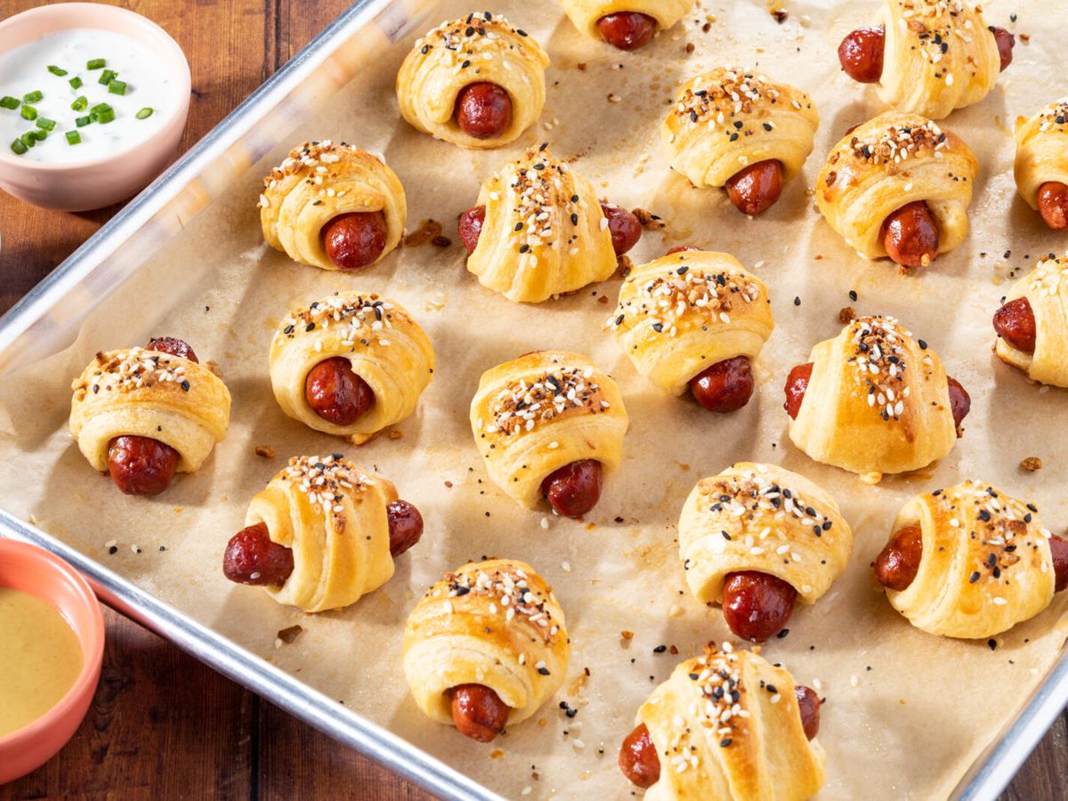 https://hips.hearstapps.com/hmg-prod/images/pigs-in-a-blanket-recipe-1-1643840836.jpg?crop=0.8891666666666667xw:1xh;center,top&resize=1200:*