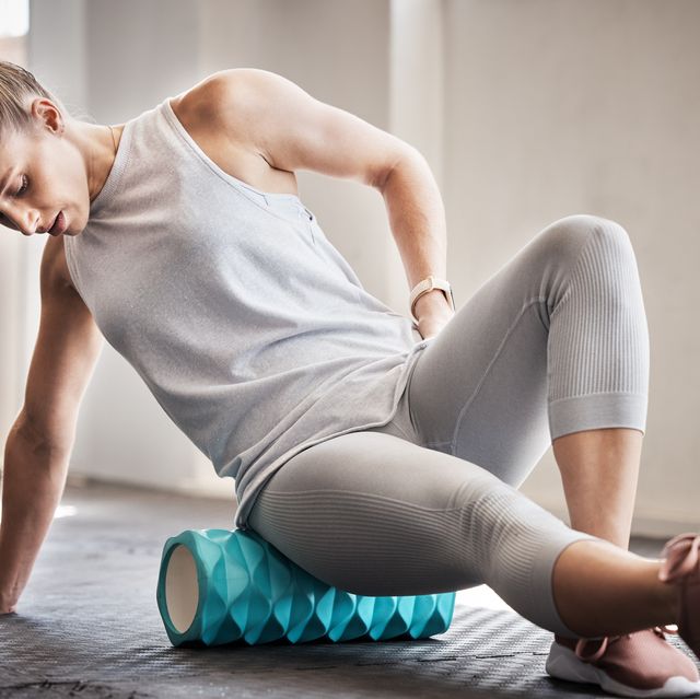 foam rolling, pilates, physiotherapy and massage, woman with foam roller on floor for leg tension and support in yoga workout at gym health, fitness and massaging for sports physio, girl on ground rolling muscle