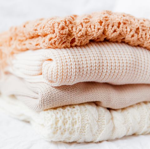Pile of beige woolen clothes on a white background.