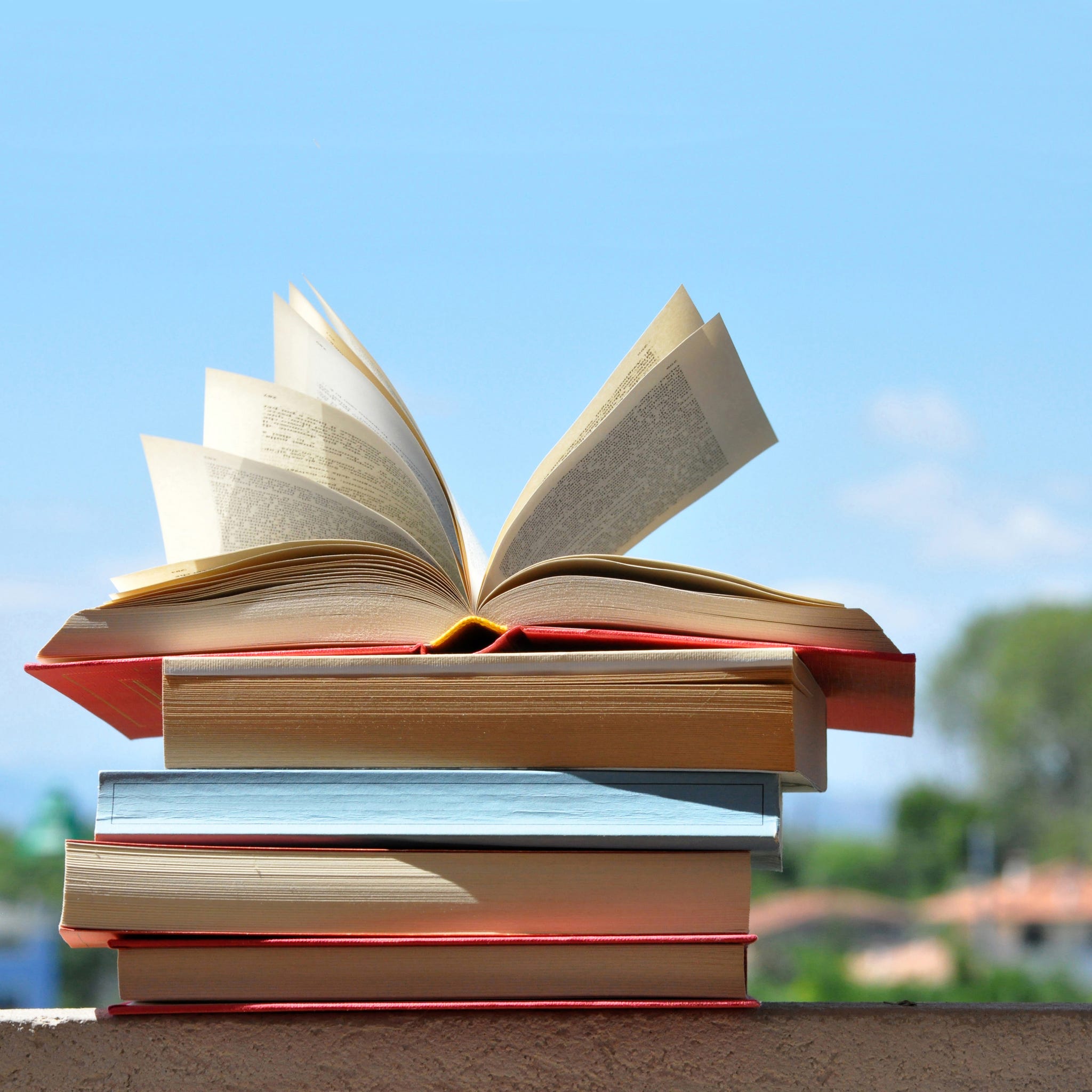 pile of books with pages open by wind