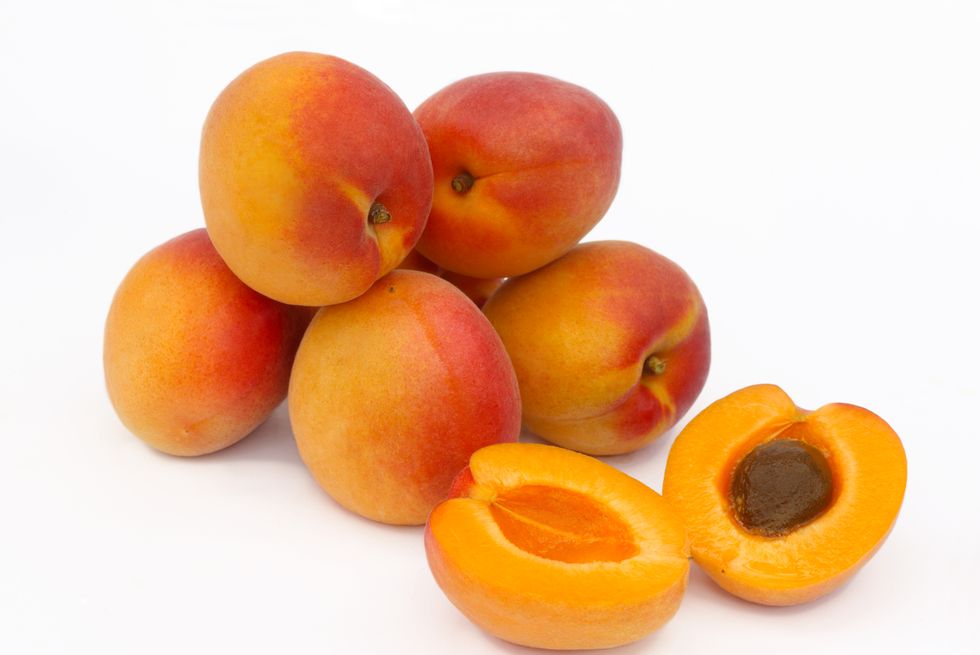 a pile of ripe apricots, one halved