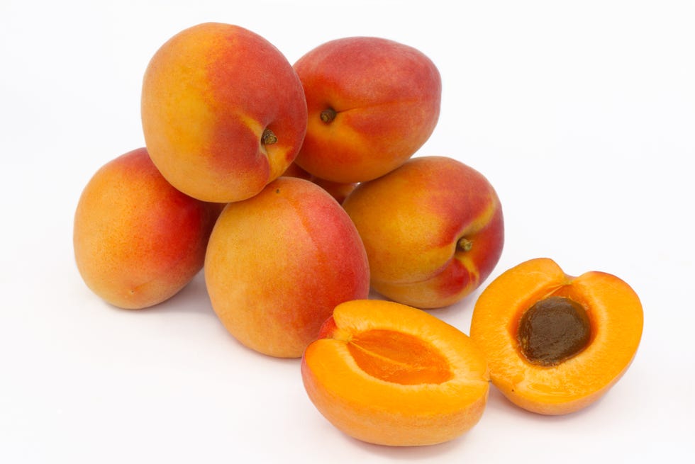 a pile of ripe apricots, one halved