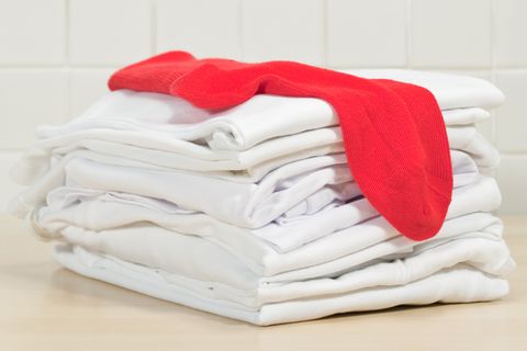 Piles of clean white laundry and red sock
