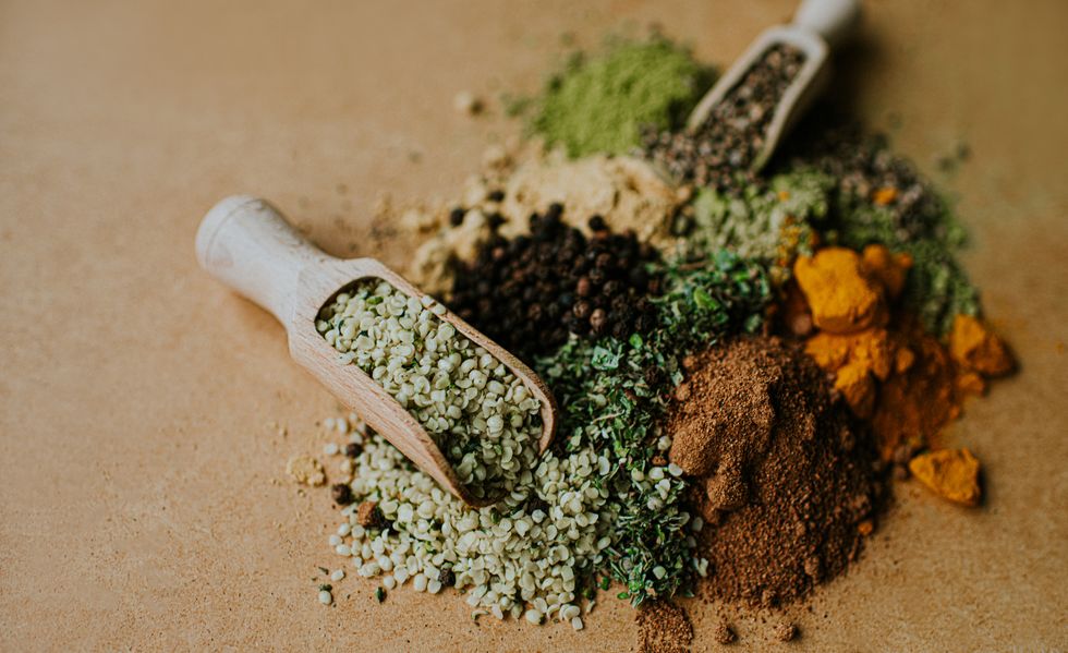 piles of herbs, spices and seasonings on a wooden surface, with scoops
