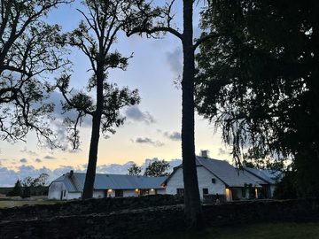 rural scene featuring a white building and trees at dusk