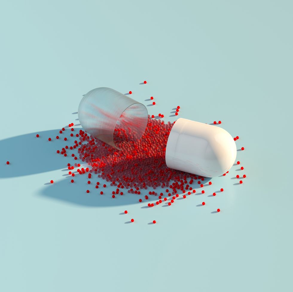 digital generated image of abstract opened plastic capsule pill with small red spheres inside on pastel blue background