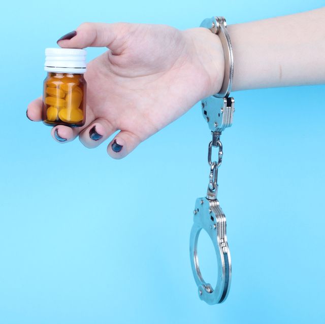 pills and tablets handcuffed hands on blue background
