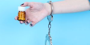 pills and tablets handcuffed hands on blue background