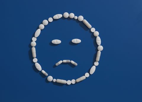 Pills forming frowning face on blue background