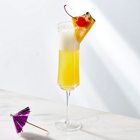 pina colada mimosa garnished with a maraschino and a pineapple wedge