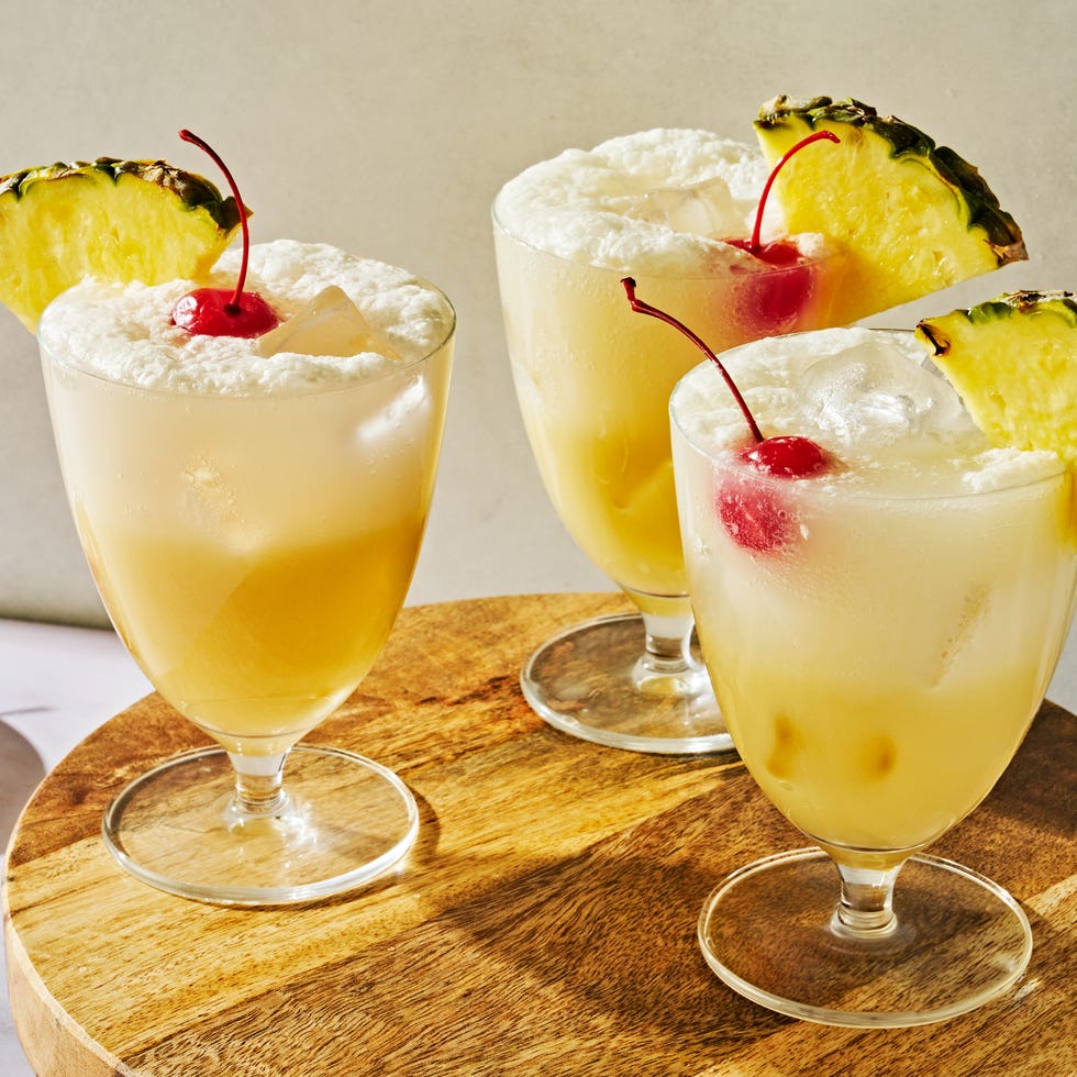 pina colada spritz topped with a maraschino cherry and a pineapple wedge