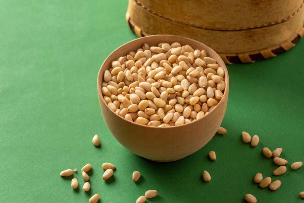 pine nuts in a bowl on a green background