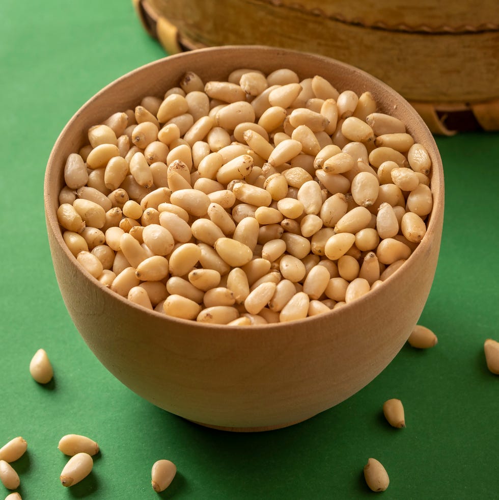 pine nuts in a bowl on a green background pine nuts in a bowl on a green background