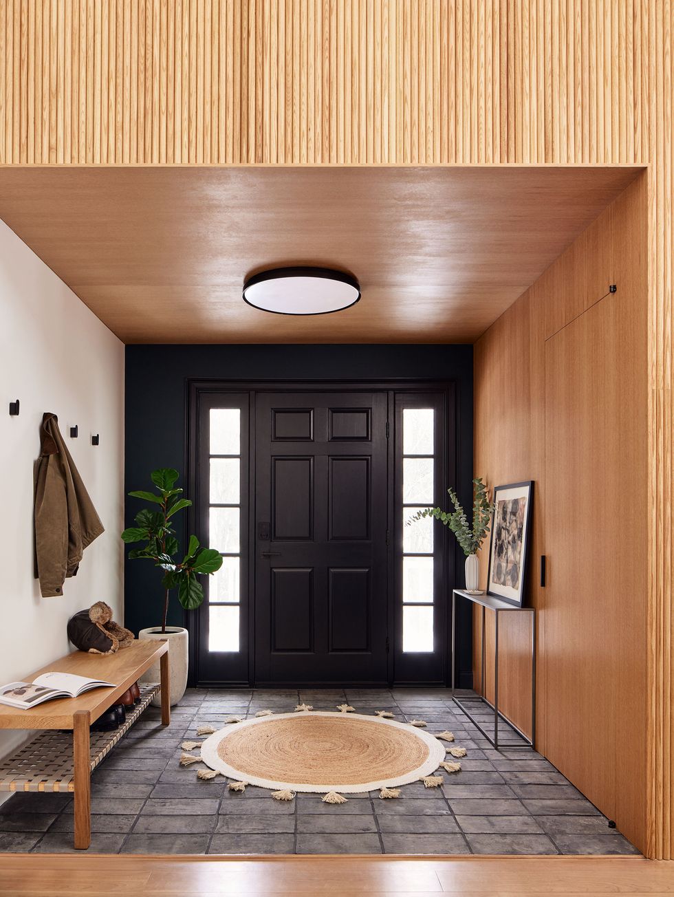 entryway with dark door with sidelights and a bench and tile on the floor and wood lined walls and ceilings