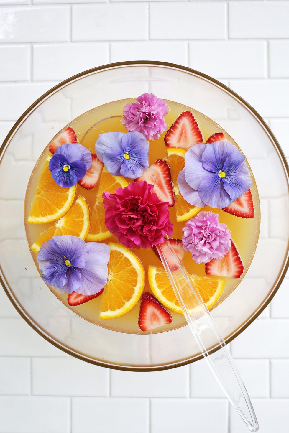 pineapple citrus punch with purple flowers, strawberries and orange slices
