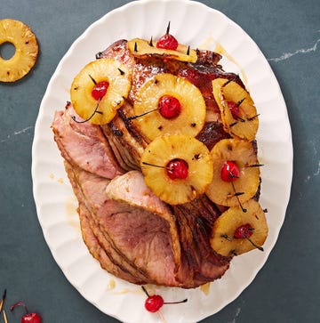 brown sugar glazed ham with pineapple rings stuck through with maraschino cherries on a white plate