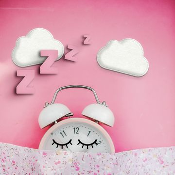 pink alarm clock sleeping in bed