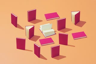 a group of books with pink covers set up on an orange background
