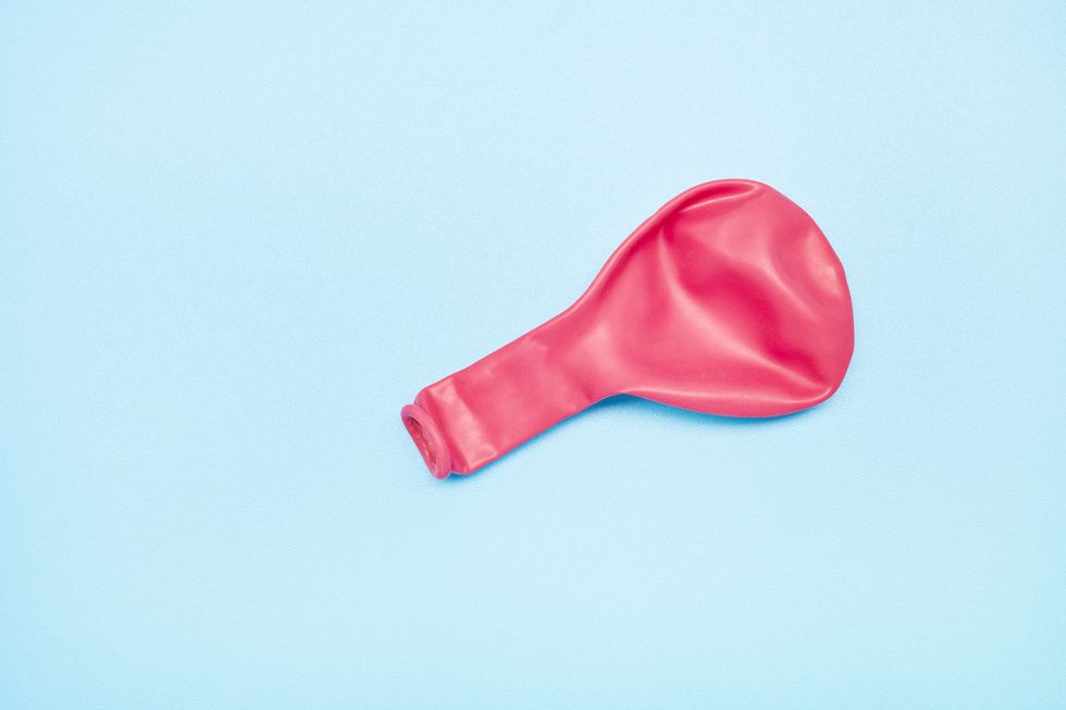 pink deflated balloon on blue background