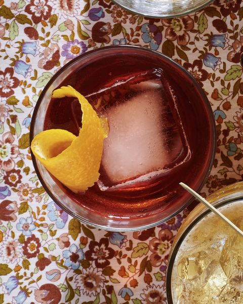 boulevardier or a bourbon negroni in a glass with a large square ice cube and orange peel for garnish