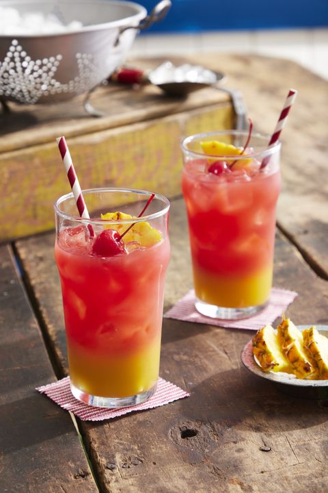 sailors warning cocktail with pineapple juice on the bottom and watermelon juice on top and garnished with a slice of pineapple and a cherry