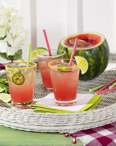 spicy watermelon cocktail in glasses with ice and garnished with sliced jalapenos and a lime wedge