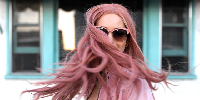 woman in sunglasses shaking out long pink hair