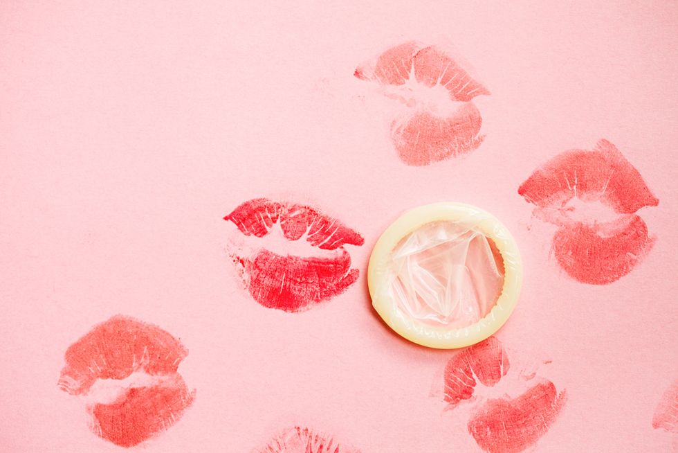Lipstick kisses on pink background with condom