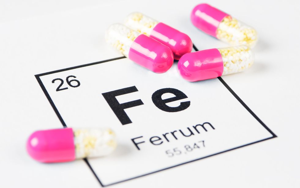 pink pills with mineral fe ferrum on a white background with an inscription from the chemical table