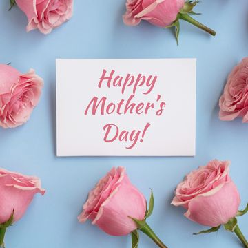pink rose flowers over blue background and paper greeting card with text happy mother's day